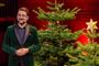 en mand med skæg ved et juletræ