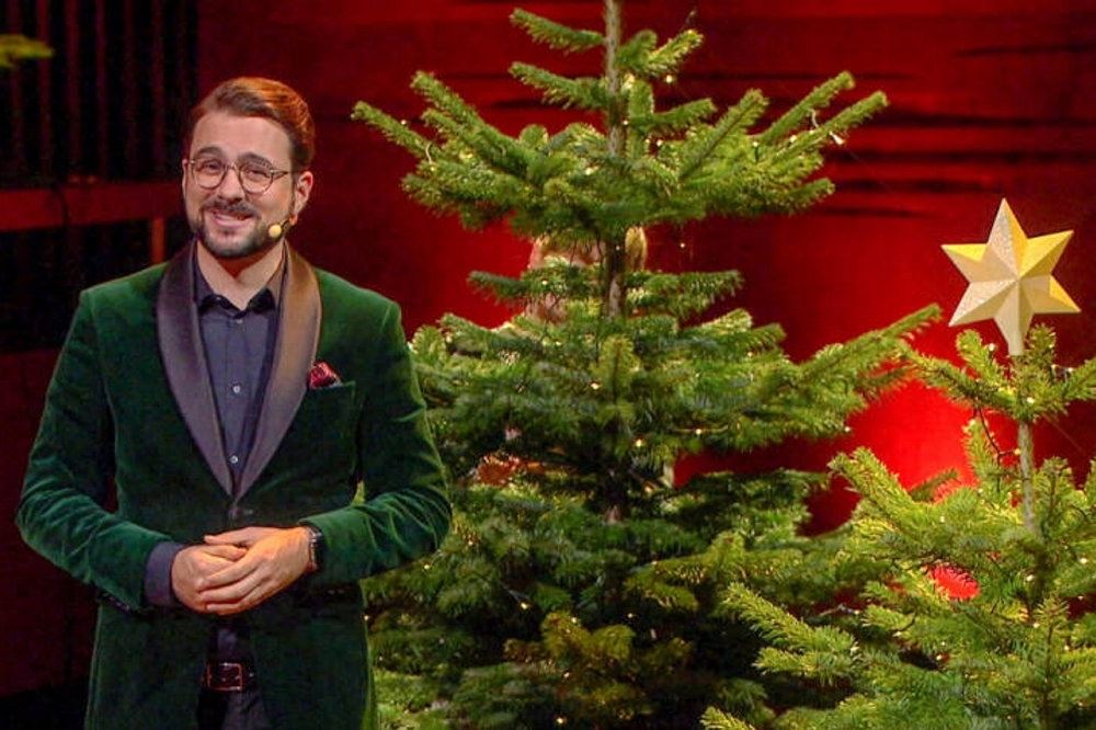 en mand med skæg ved et juletræ