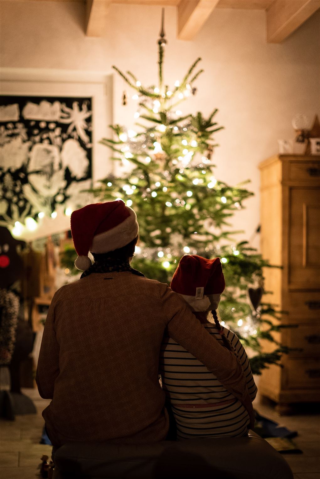 Et søskendepar sidder foran et juletræ