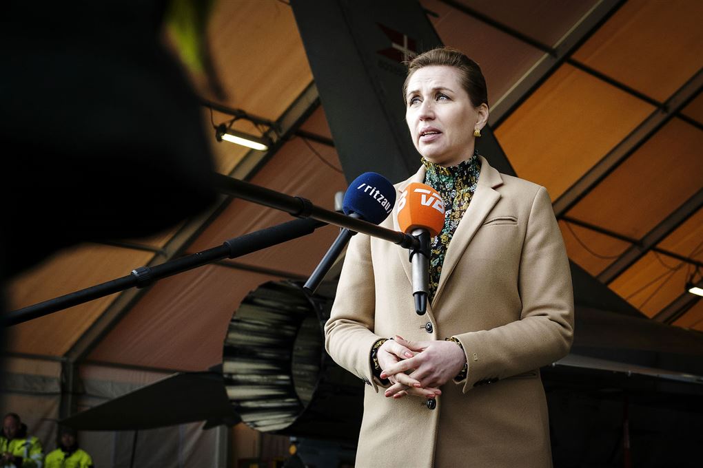 Mette Frederiksen i en hangar hun taler ind i mikrofoner fra Ritzau og TV2