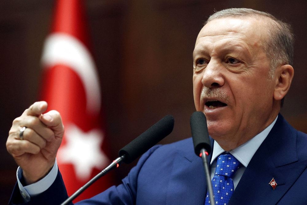 en tvær ældre mand med knyttet næve og tyrkisk flag i baggrunden