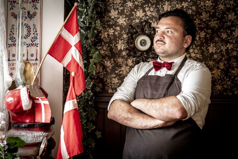 mand i forklæde står ved danske flag