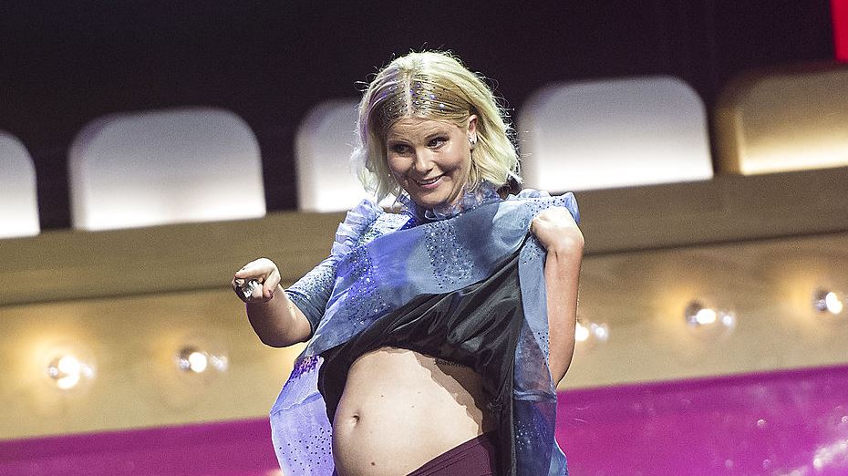 En blond dame på en scene viser mave og trusser
