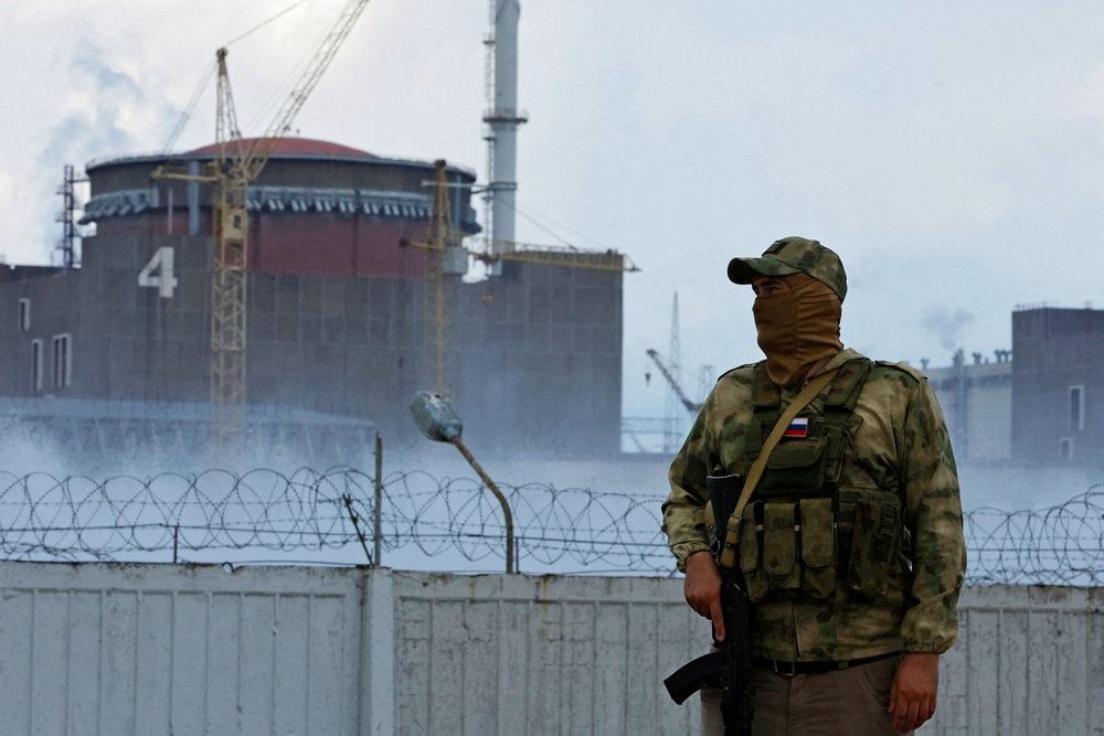 En soldat med et russisk flag på uniformen holder vagt ved atomkraftværket Zaporizjzja.