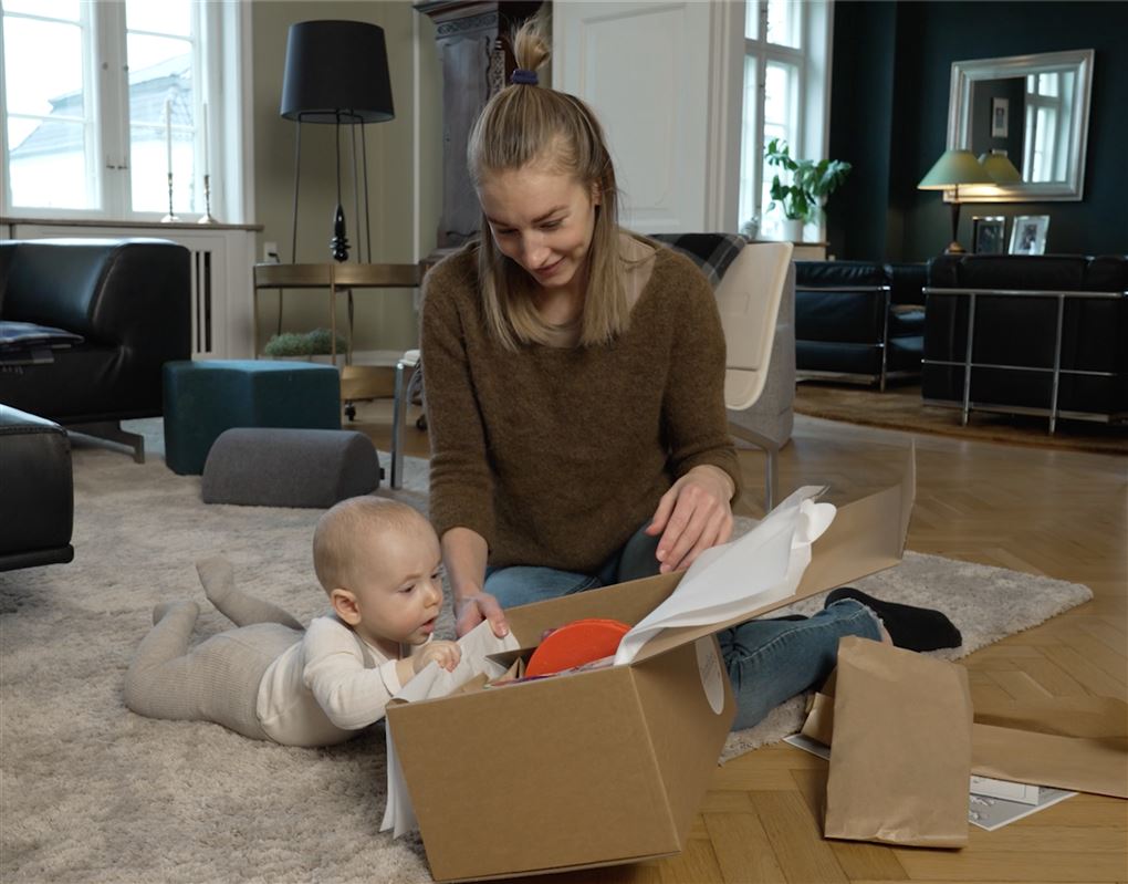 en mor og hendes baby i en stue med en papkasse