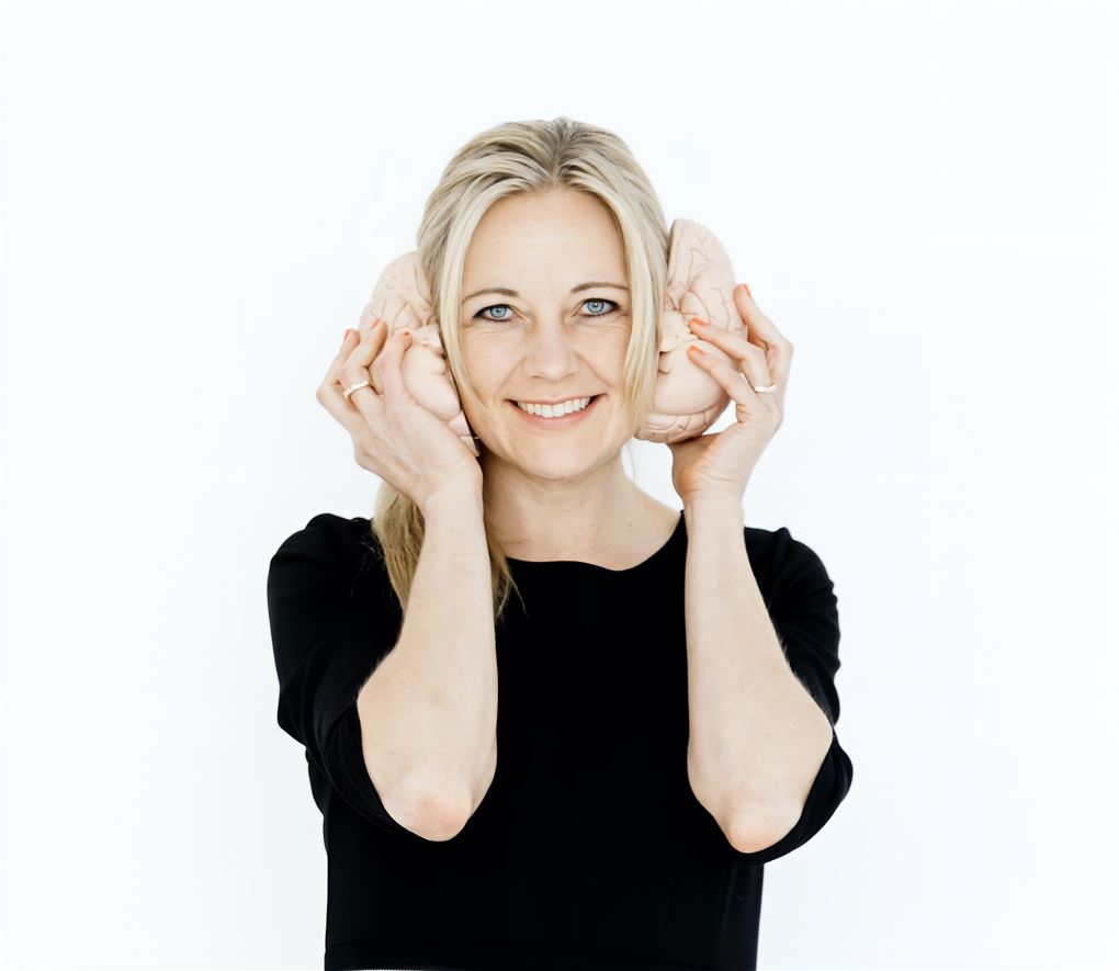 En kvinde holder to hjernehalvdele op til ørene
