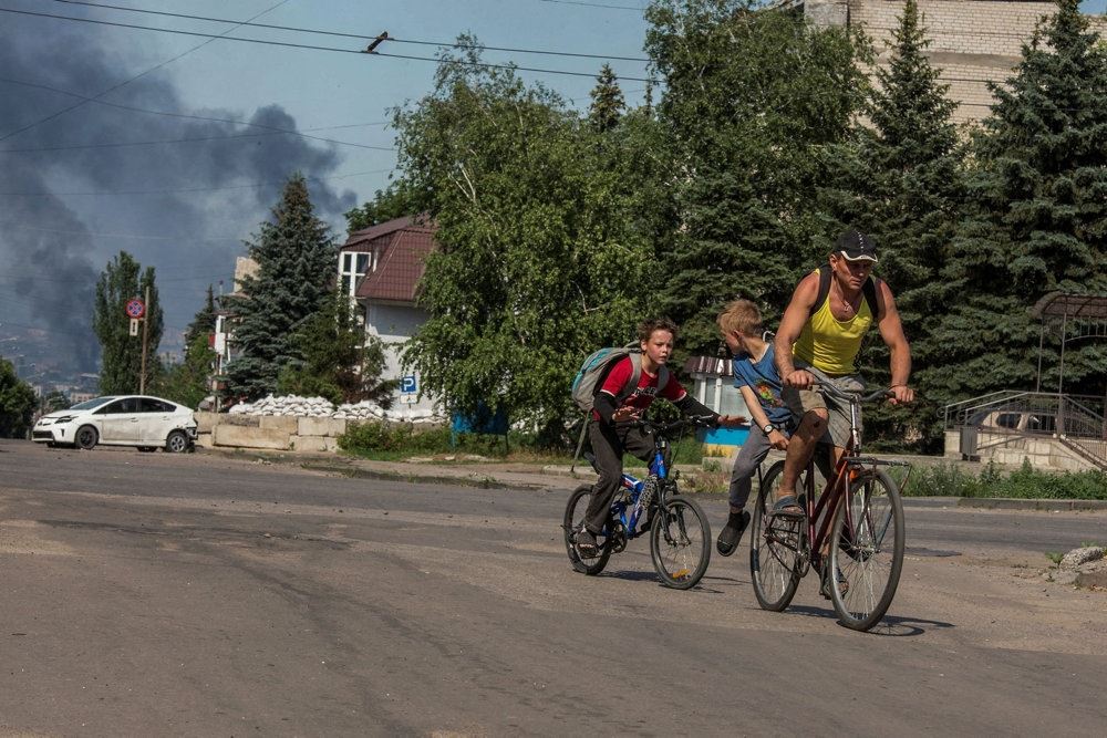 Børn flygter på cykel fra eksplosioner