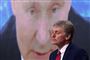 en mand ved siden af et stort billede af Putin