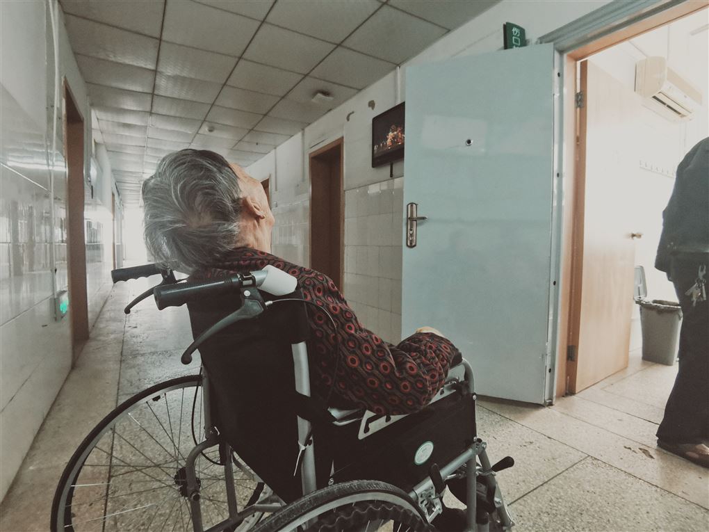En person i en kørestol på en hospitalsgang med ryggen til