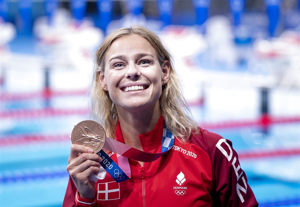 kvinde smiler med medalje i hånden