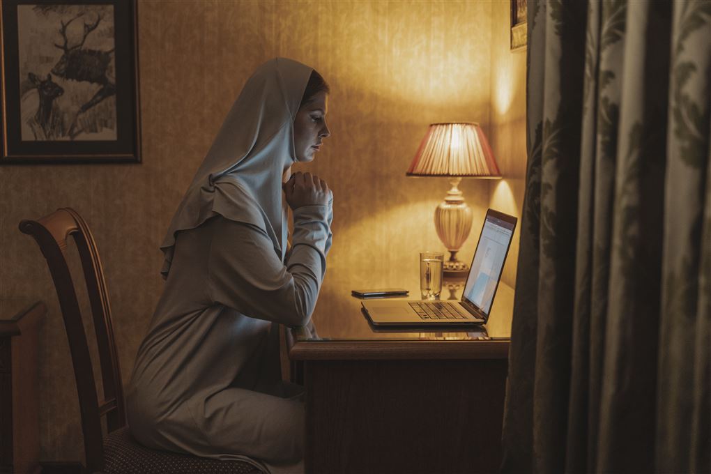 en nonne ved et skrivebord og en pc