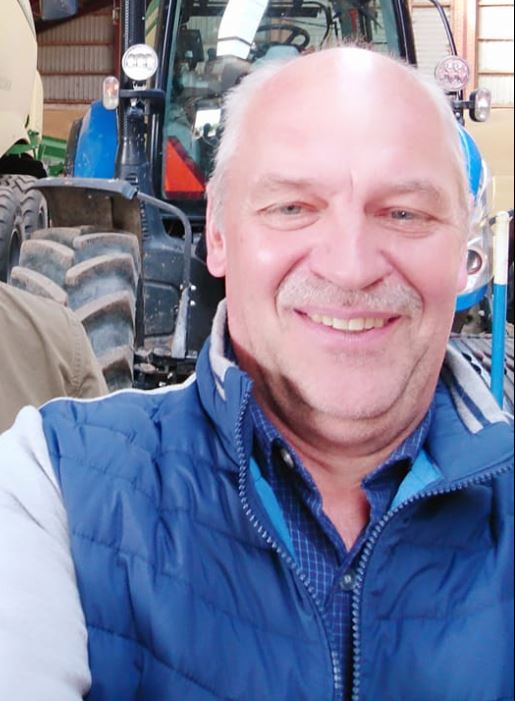 En mand smiler foran en traktor