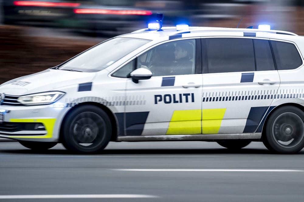 En politibil set fra siden. Den er hvid med blå skrift.
