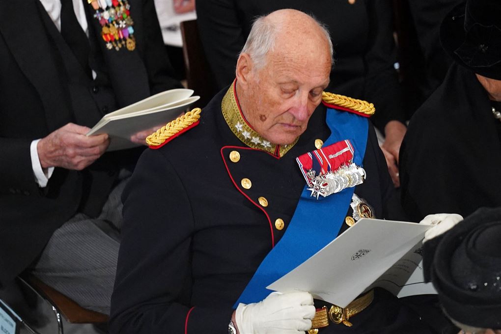 Kong Harald med en stor hvid folder som han kigger i.