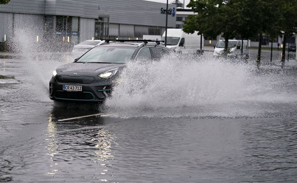 en bil kører gennem kæmpe vandpyt