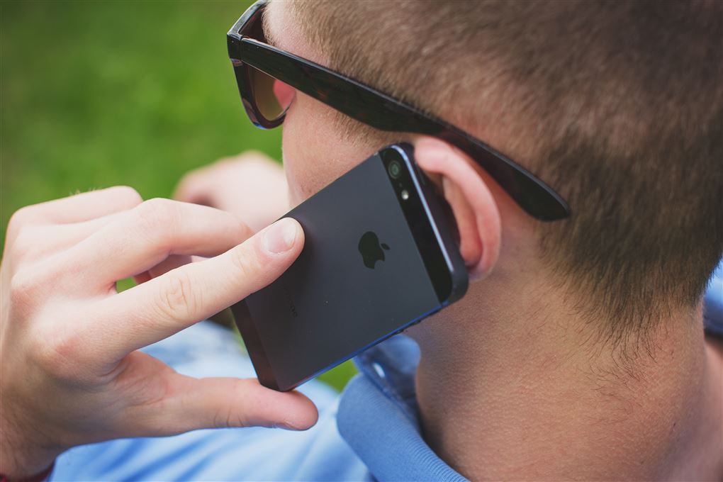 En mand med en iPhone han ses fra ryggen