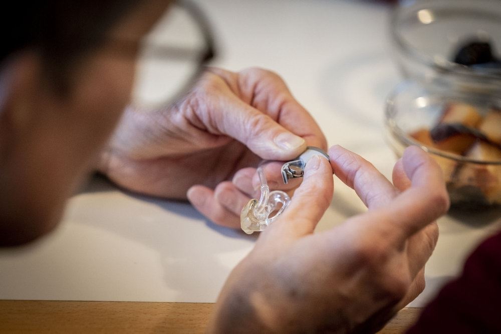 person sidder med høreapparat 