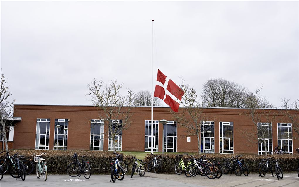 en flagstang med flaget på halv ved en skole