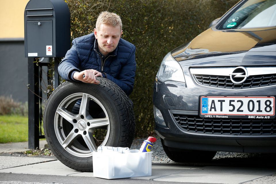 En mand sidder ved en bil med et dæk