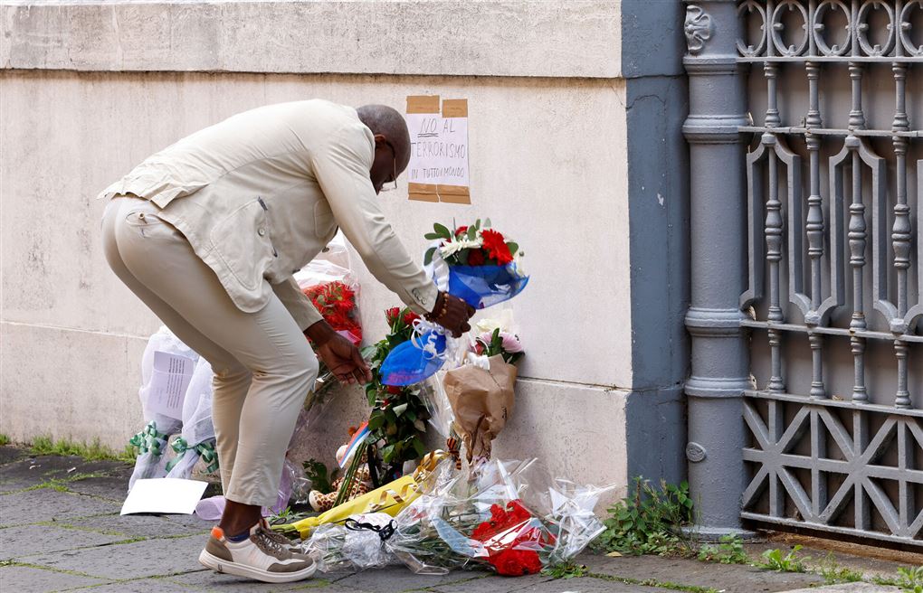 En mand lægger blomster ved en mur
