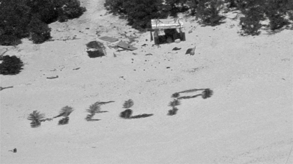 Ordene "HELP" lavet med palmeblade på en strand.