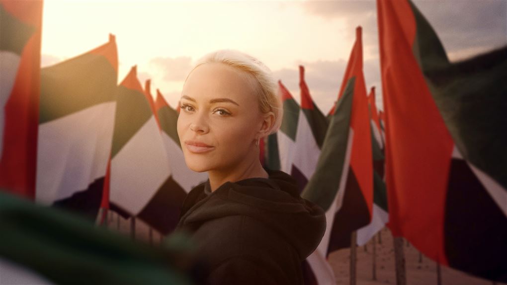 Lyshåret kvinde foran flag