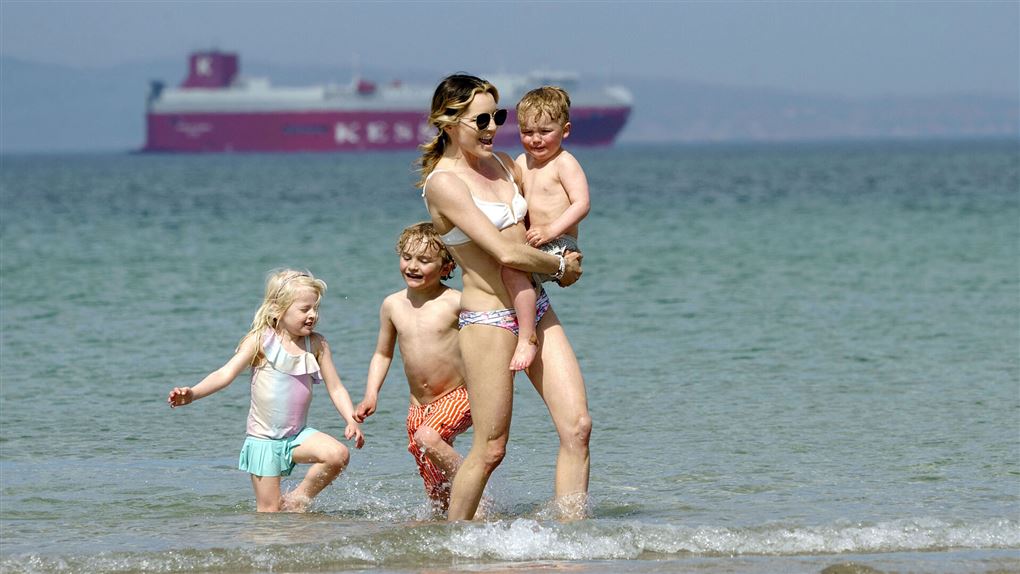 en kvinde og børn i strandkanten