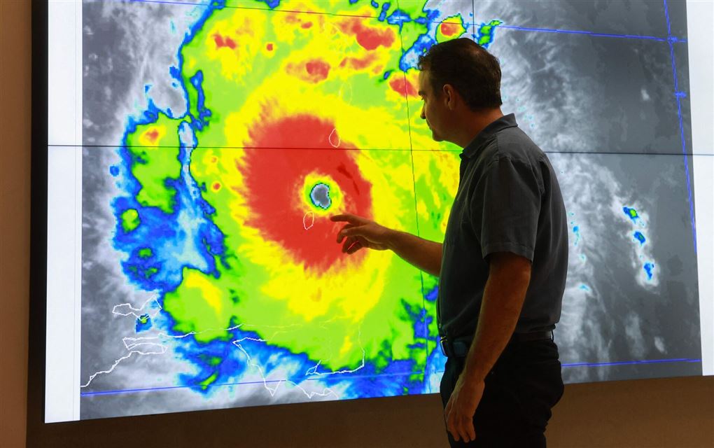 mand står ved vejrkort med orkan