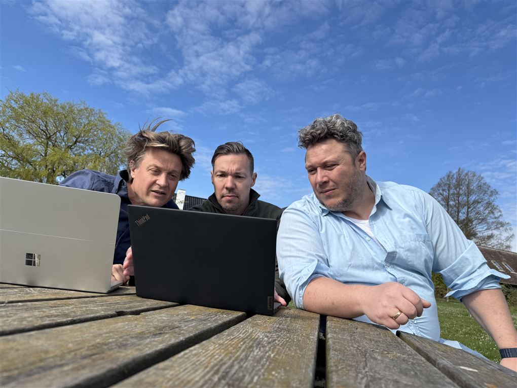 3 mænd kigger på en skærm i solen