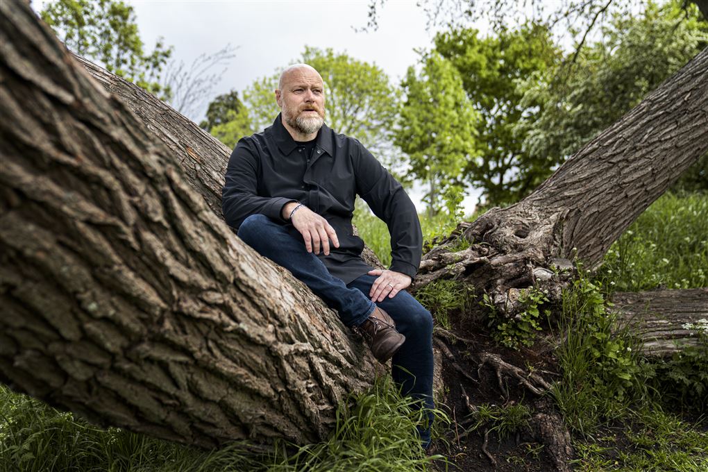 Mand sidder overn på en træstamme