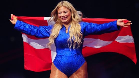 kvinde på scene i blå jumpsuit med dannebrog bag ryggen