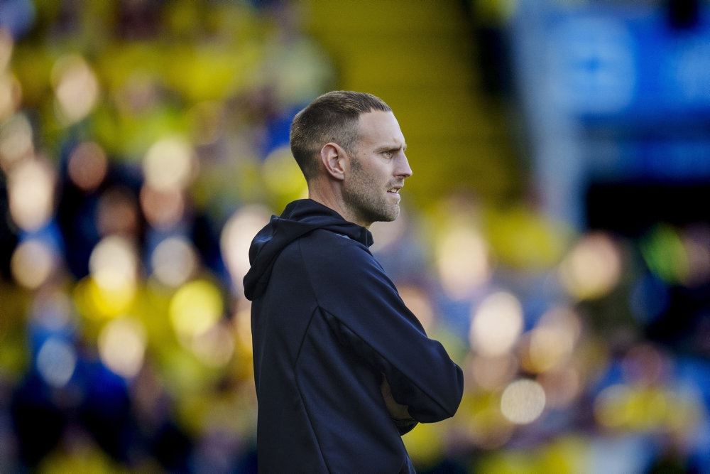 mand med korsklagte arme påp sidelinien på stadion