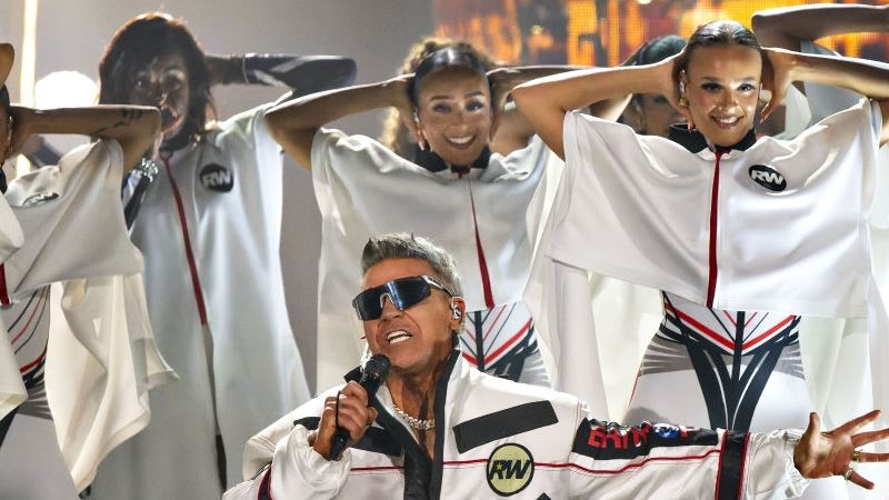 sangeren robbie williams omgivet af sin stab