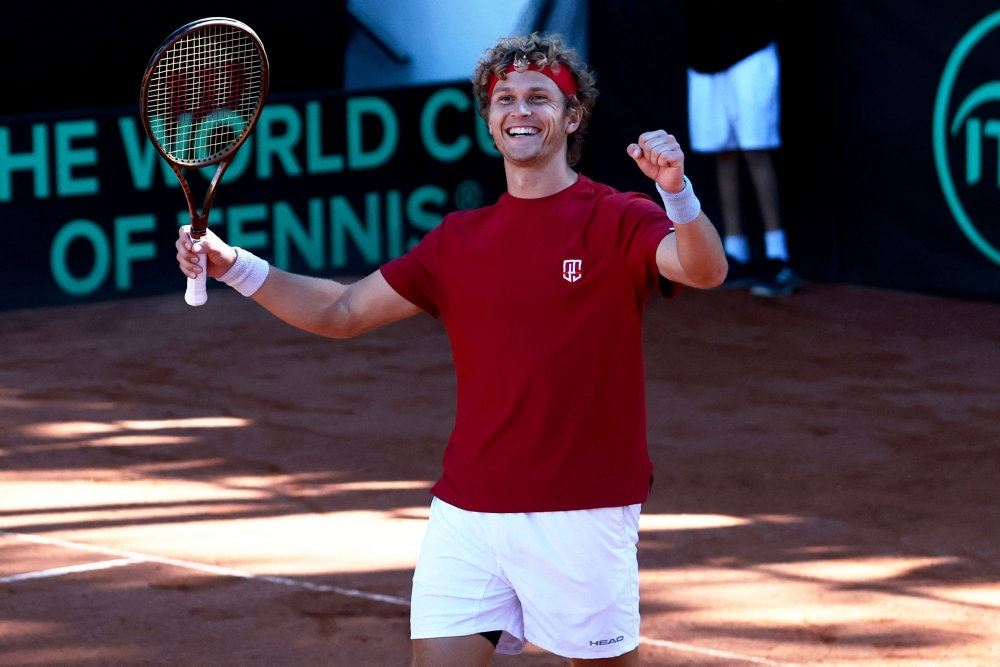 en tennisspiller løfter armen i sejrsglæde