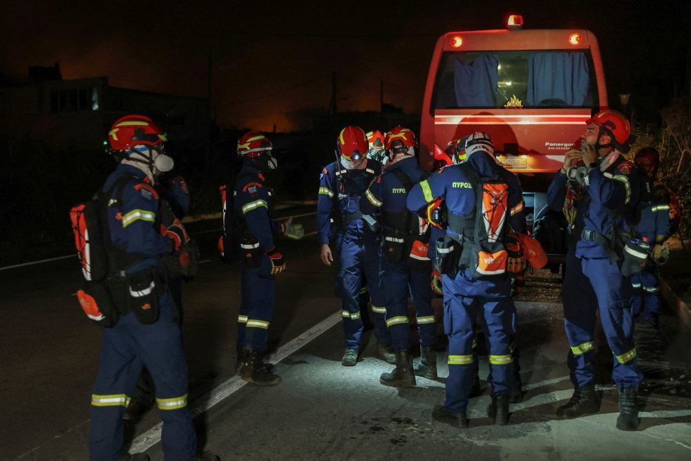 Brandmænd i fuld uniform foran brandbil