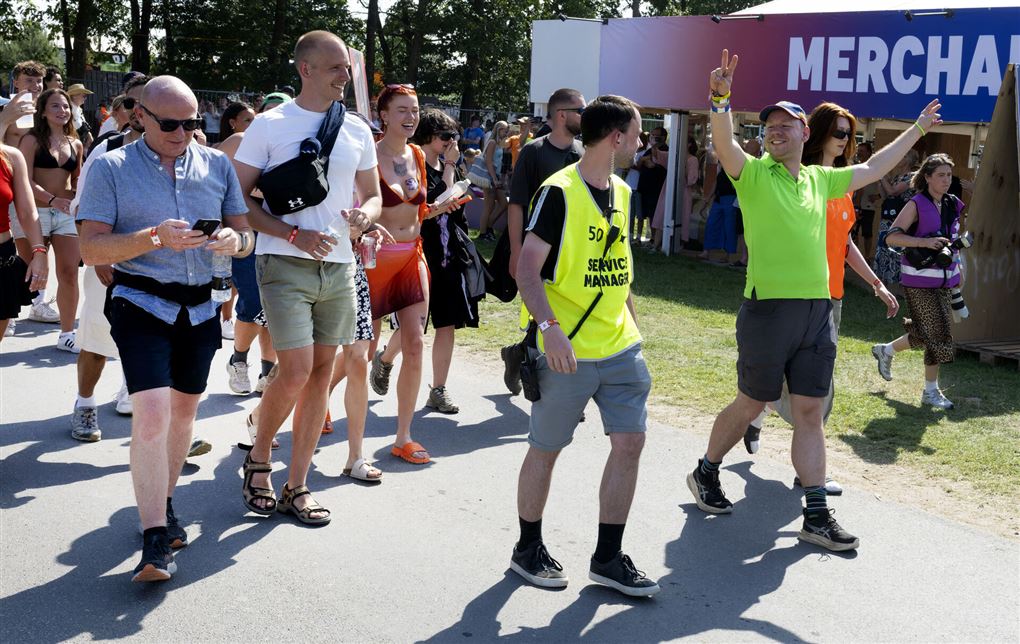 En masse glade festivalgængere går ind på festivalpladsen.
