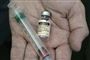 En hånd holder en sprøjte og vaccine