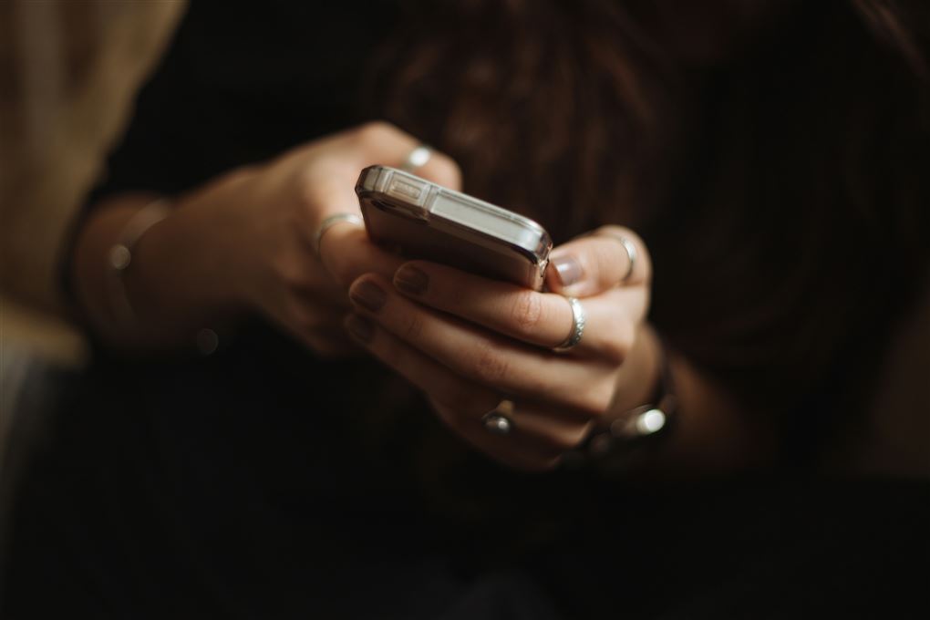 person står med mobiltelefon i hånden