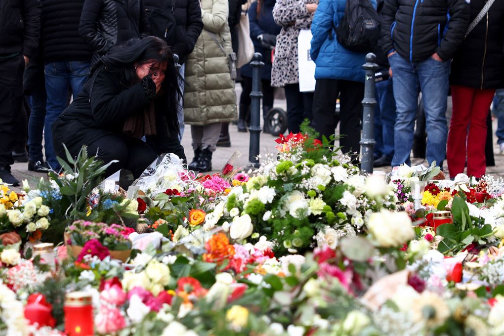 folk kigger på blomster og lys mindested