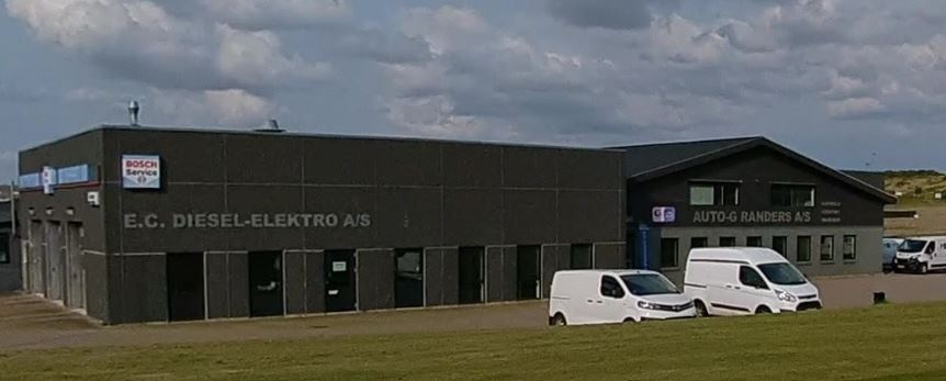 Facaden af et autohus, hvor to hvide varebiler holder udenfor