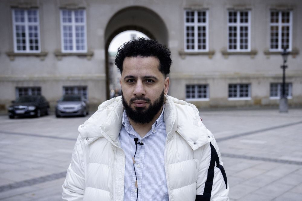 Samsam på vej til retssag iført hvid dunjakke og skjorte